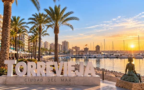 Torrevieja seafront at sunset, with the marina, palm trees and apartment blocks